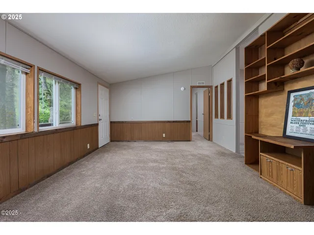 a view of an empty room with furniture and window