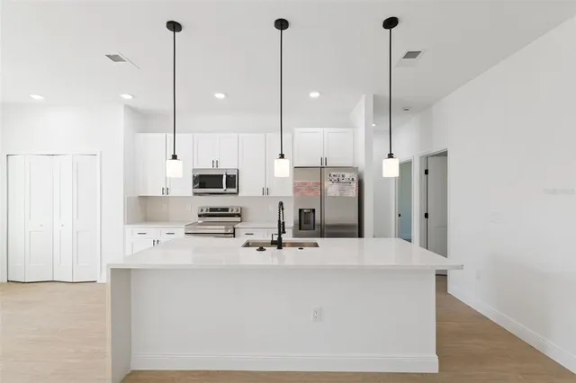 a kitchen with stainless steel appliances kitchen island granite countertop a sink a center island a stove and a wooden floor