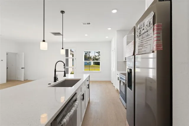 a kitchen with stainless steel appliances a refrigerator a sink a stove and chairs