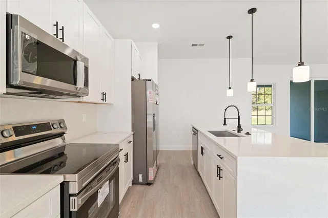 a kitchen with stainless steel appliances granite countertop a sink a stove and a wooden floor