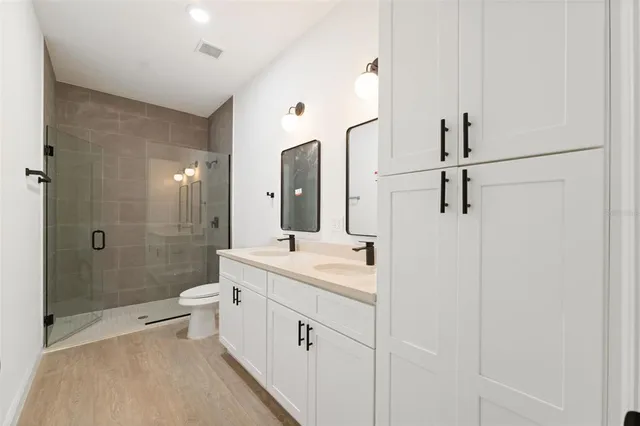 a bathroom with a double vanity sink toilet mirror and shower