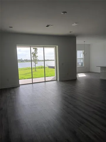 an empty room with wooden floor and a floor to ceiling window
