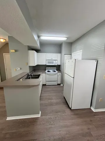 a kitchen with a refrigerator a stove top oven and wooden floor