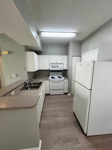 a kitchen with a refrigerator a sink and white cabinets