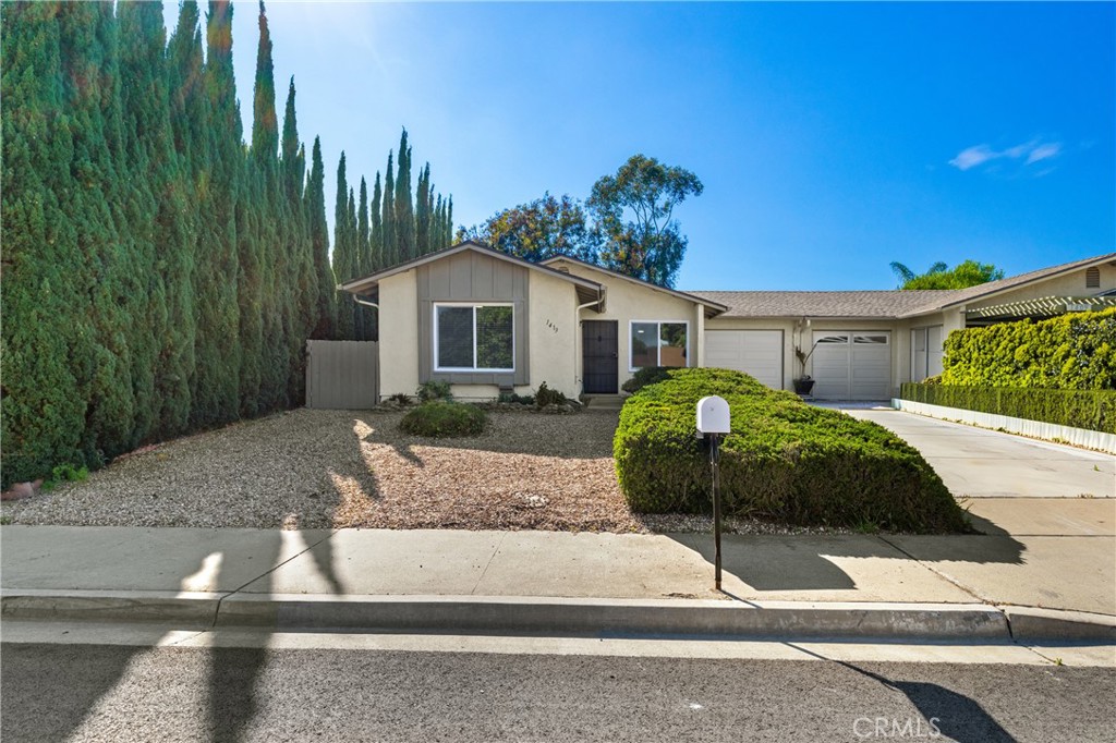 a front view of a house with a yard and potted plants
