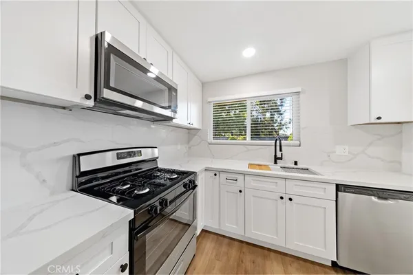 a kitchen with stainless steel appliances a sink dishwasher stove and cabinets