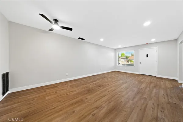 an empty room with wooden floor cabinet and windows