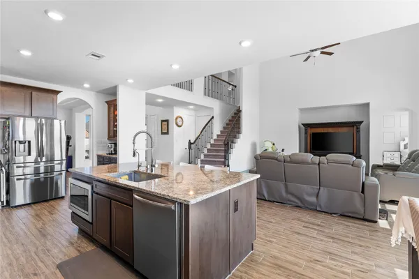 a living room with stainless steel appliances kitchen island granite countertop a stove and a wooden floors