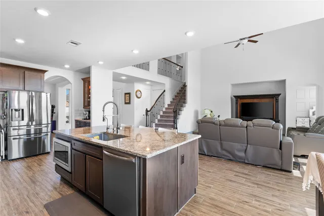 a living room with stainless steel appliances kitchen island granite countertop a stove and a wooden floors