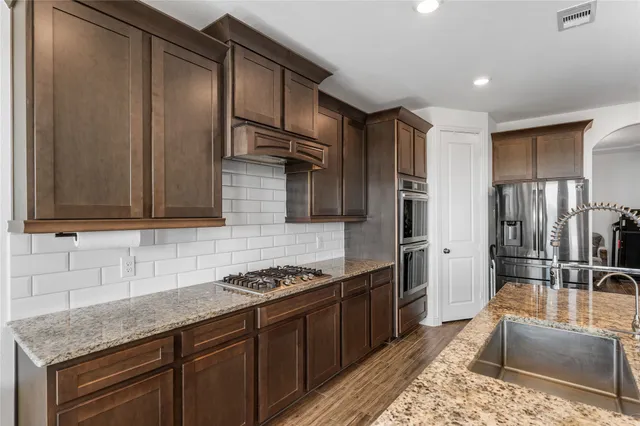 a kitchen with stainless steel appliances granite countertop a sink stove and refrigerator