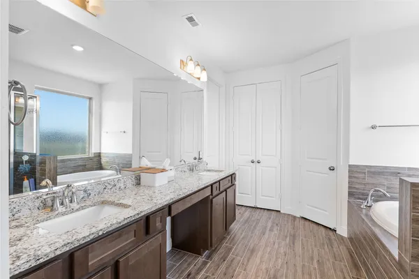 a bathroom with a granite countertop double vanity sink and mirror