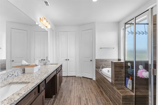 a spacious bathroom with a granite countertop sink a mirror and shower