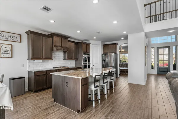 a kitchen with stainless steel appliances granite countertop wooden floors and table