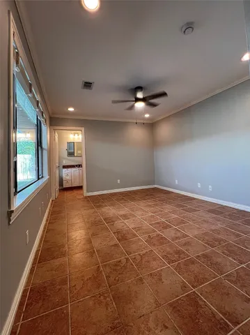 a view of an empty room with window and chandelier fan