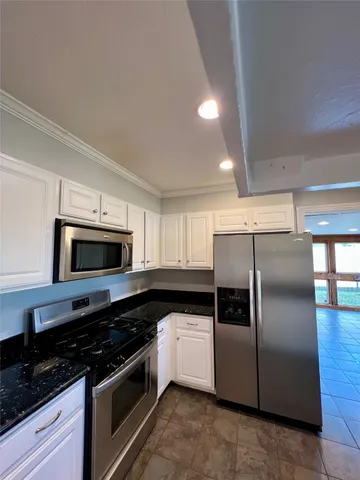a kitchen with granite countertop a sink window and cabinets