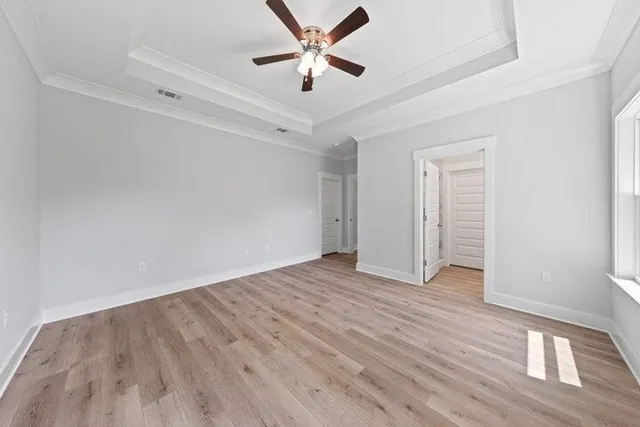 an empty room with wooden floor and ceiling fan