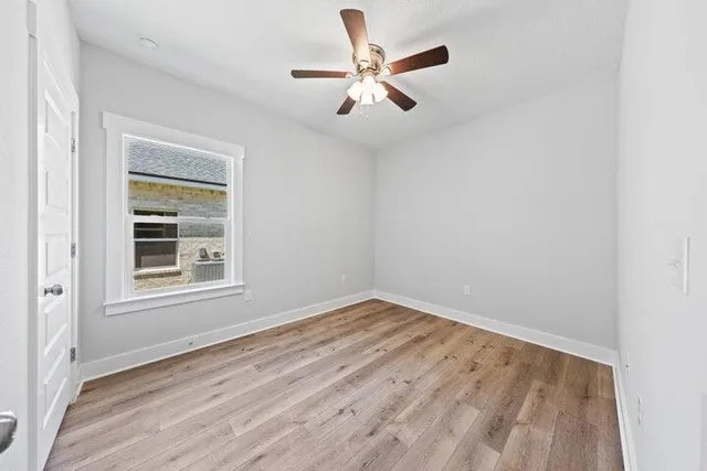 an empty room with a window and ceiling fan