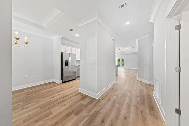 a view of a hallway with wooden floor and a refrigerator