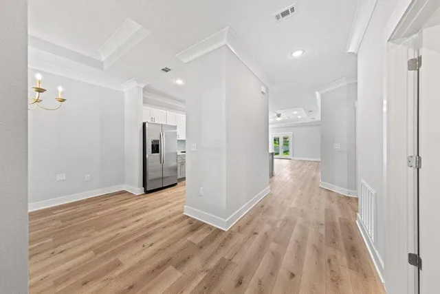 a view of a hallway with wooden floor and a refrigerator