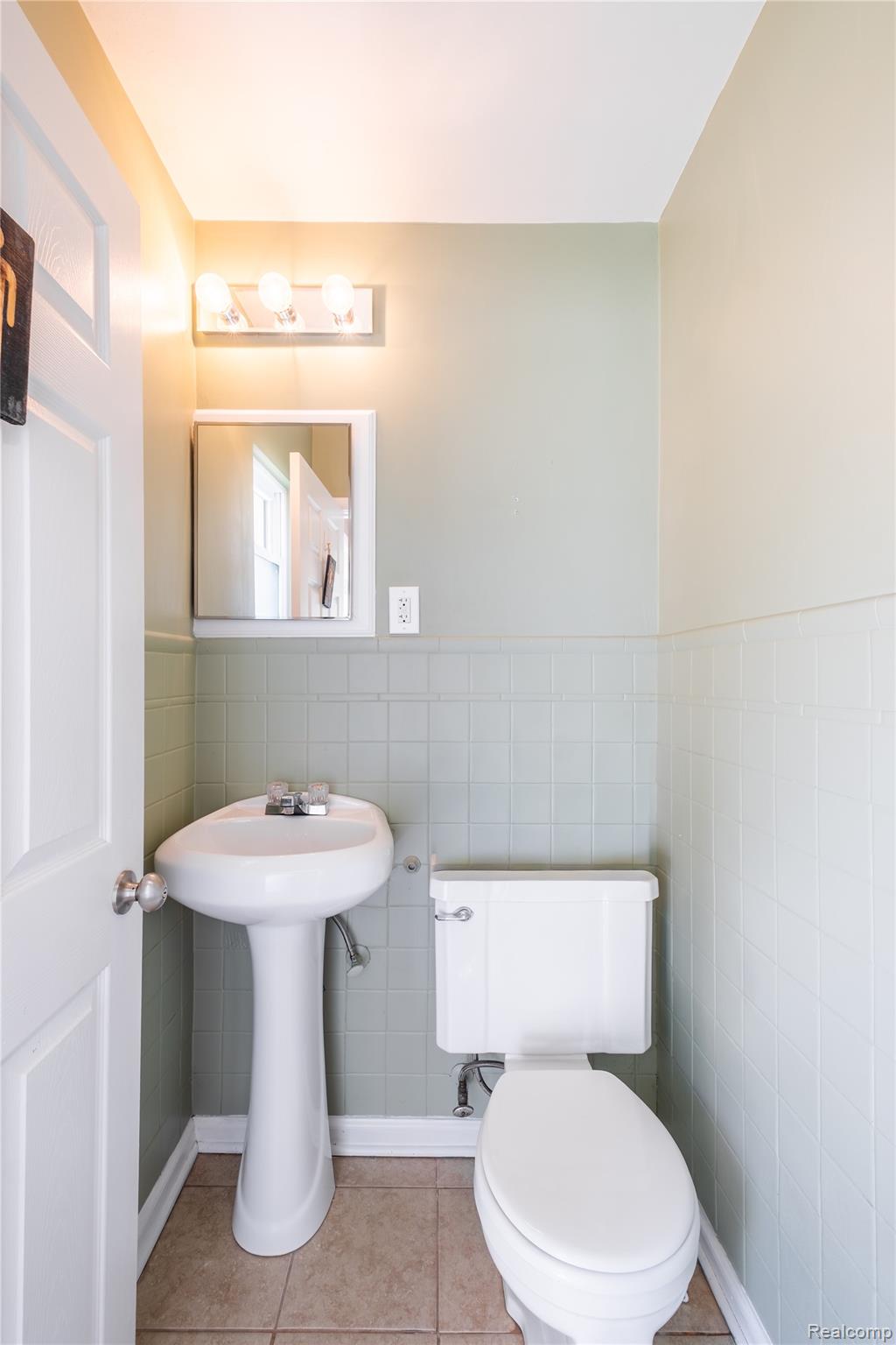 2432 Farrand Road Clio, MI 48420 - Photo 15 of 27 Pedestal sink, wall-mounted mirror, ceramic tile flooring, and a three-light vanity fixture