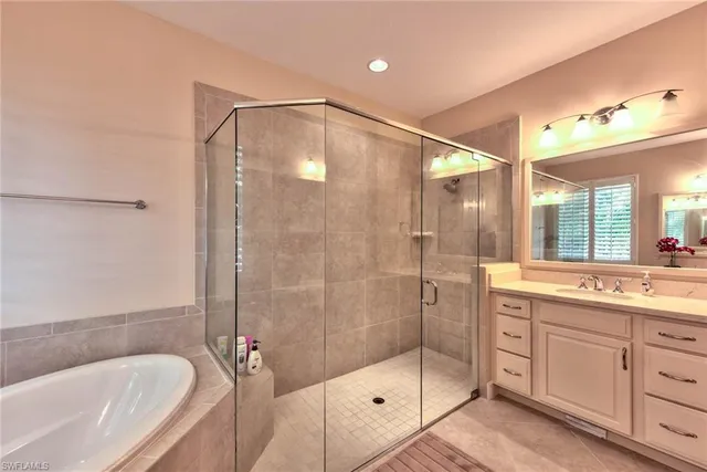 a bathroom with a bathtub shower sink vanity and mirror