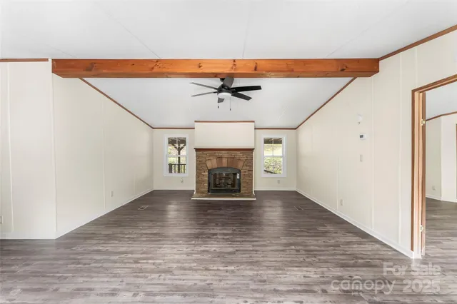 an empty room with chandelier fan and wooden floor