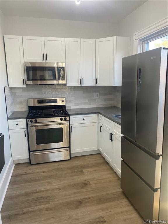 a kitchen with stainless steel appliances white cabinets white and wooden floor