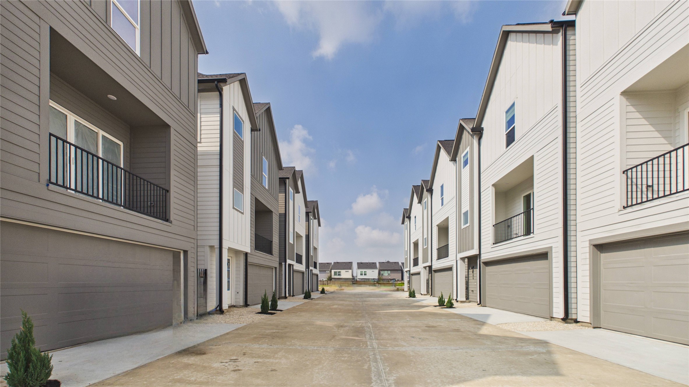 602 Skyland Terrace Way Houston, TX 77009 - Photo 3 of 40 Modern townhouse community with clean lines and uniform design. Each unit features a garage, balcony, and neutral exterior colors. The wide driveway provides ample space, and there are small landscaped areas with young plants.