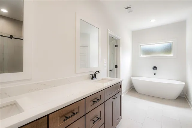 a bathroom with a double vanity sink mirror and bathtub