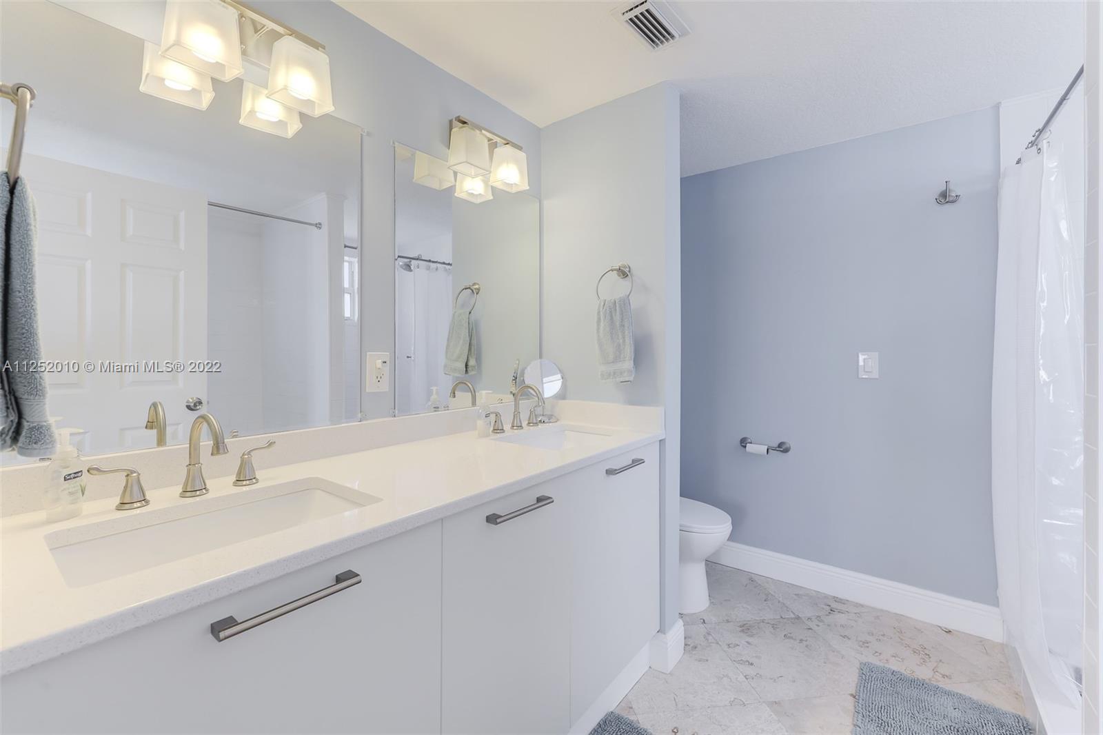 1037 Southwest 9th Court, Unit E1 Miami, FL 33130 - Photo 15 of 26 a bathroom with a double vanity sink mirror and toilet