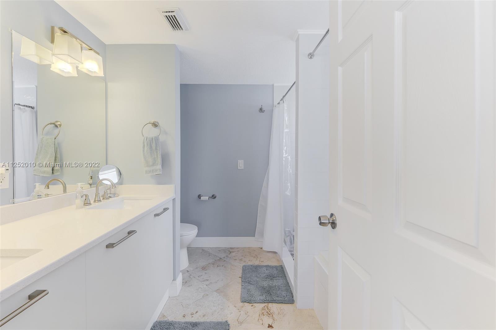 1037 Southwest 9th Court, Unit E1 Miami, FL 33130 - Photo 16 of 26 a spacious bathroom with a sink a mirror and a shower