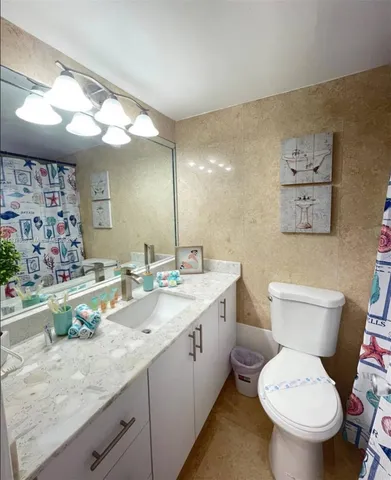 a bathroom with a granite countertop toilet sink and mirror