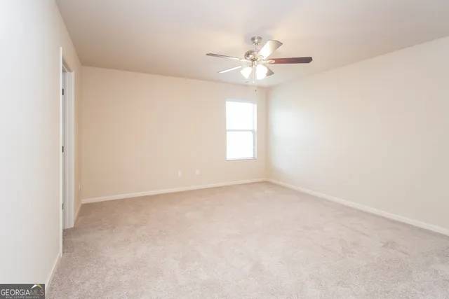 an empty room with windows and chandelier fan