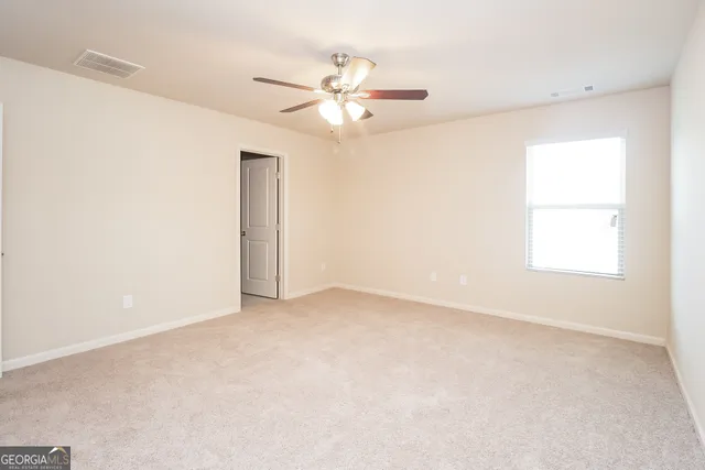 an empty room with a window and a fan