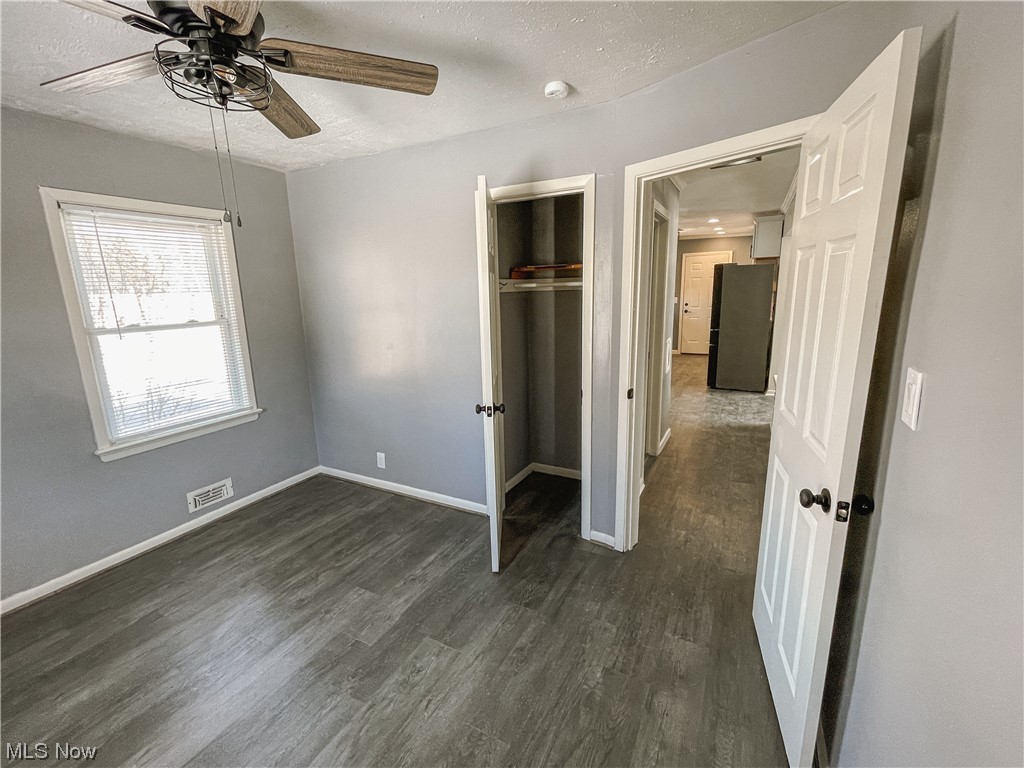 24709 Emery Road Warrensville Heights, OH 44128 - Photo 14 of 34 Unfurnished bedroom with a textured ceiling, ceiling fan, a closet, black refrigerator, and dark hardwood / wood-style flooring