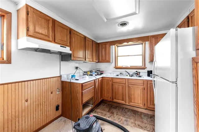 a kitchen with stainless steel appliances granite countertop a stove a sink and a refrigerator with wooden cabinets