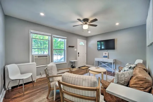 a living room with furniture a flat screen tv and a large window
