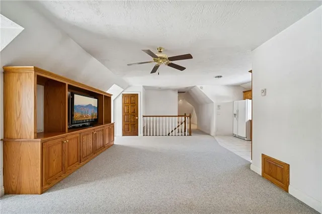 a view of a livingroom with a flat screen tv ceiling fan and stairs