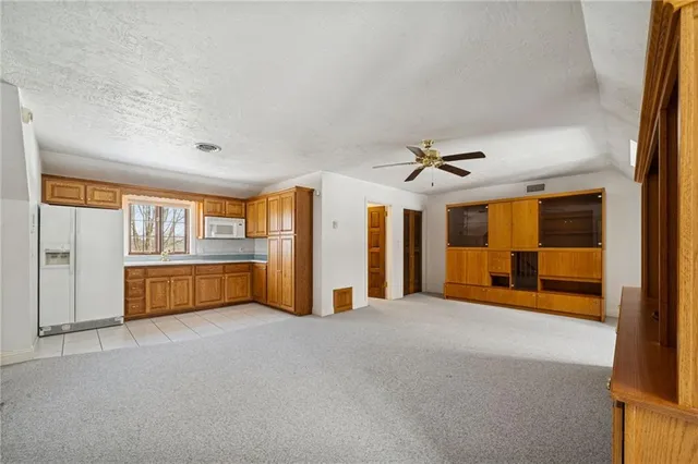 an empty room with chandelier fan and windows