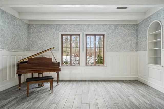 a living room with a piano a rug and a window