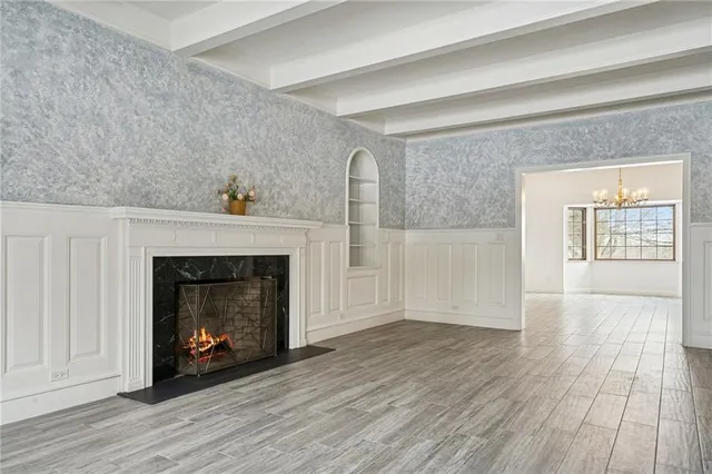 a view of an empty room with wooden floor and a fireplace