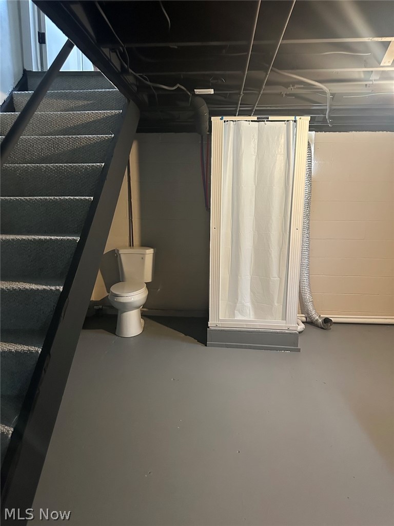 628 Creed Street Struthers, OH 44471 - Photo 20 of 20 Basement space featuring a white toilet fixture, a white shower enclosure with a shower curtain, and a gray painted concrete floor