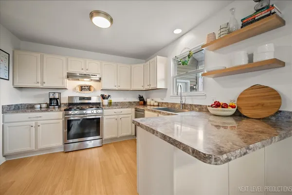 a kitchen with stainless steel appliances granite countertop a sink dishwasher and white cabinets with wooden floor