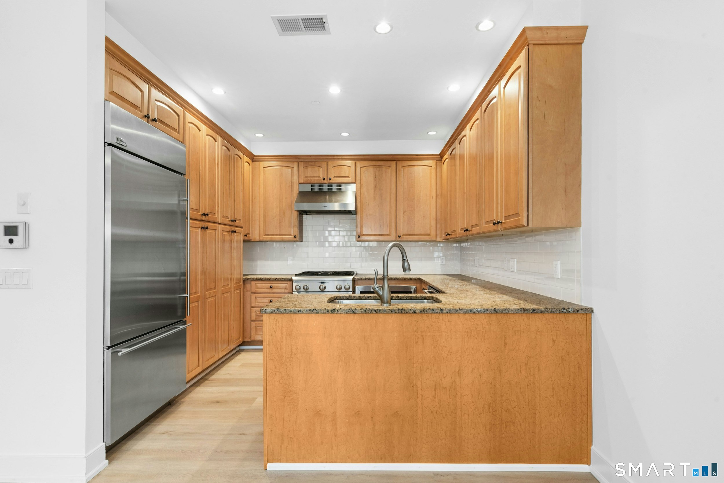 77 Havemeyer Lane, Unit 310 Stamford, CT 06902 - Photo 9 of 22 a kitchen with stainless steel appliances granite countertop a refrigerator a stove and a sink with wooden floor