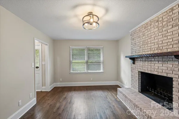 a view of empty room with wooden floor and a fireplace
