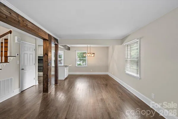 a view of an empty room with wooden floor and windows