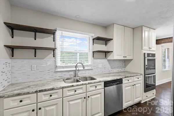 a kitchen with granite countertop a sink stainless steel appliances and cabinets