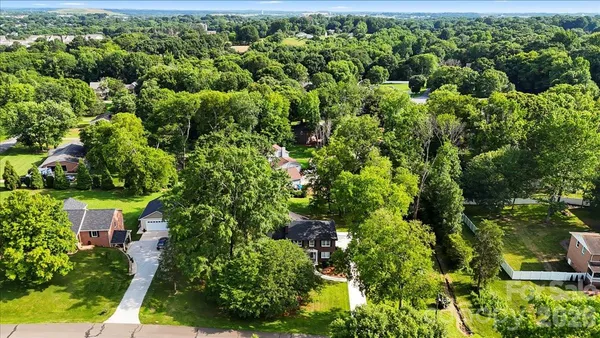 an aerial view of residential house with outdoor space and trees all around