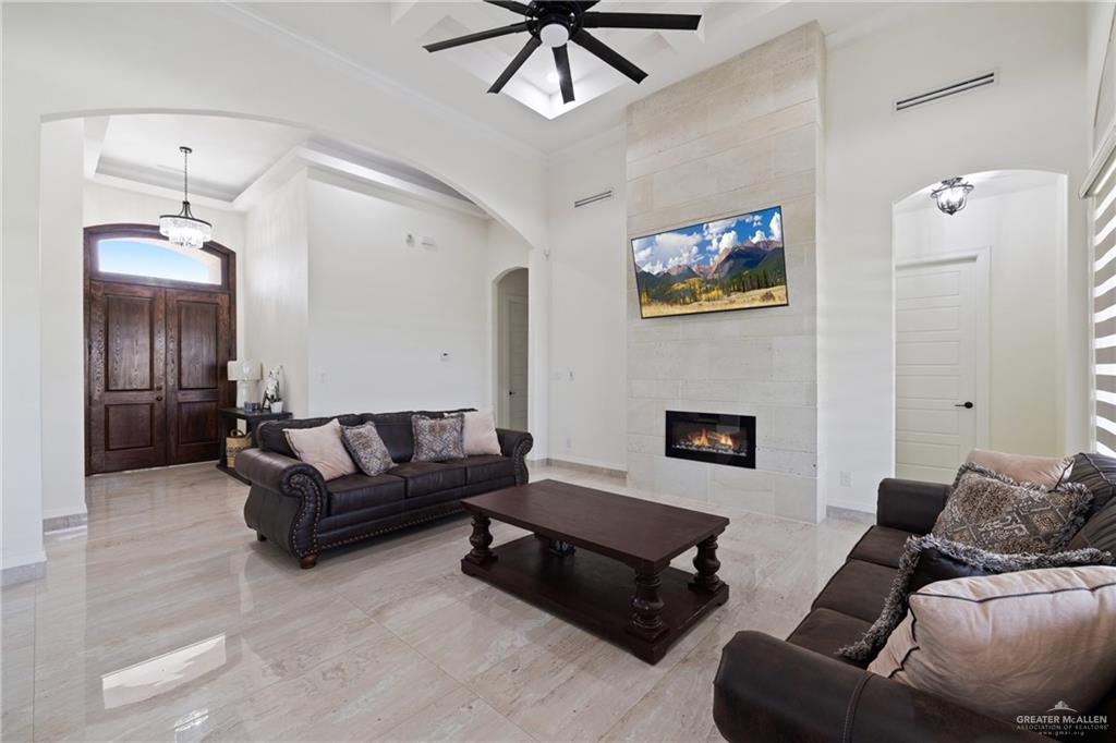 22303 Uresti Road Edinburg, TX 78542 - Photo 5 of 22 Living area with a high ceiling, arched walkways, a ceiling fan, ornamental molding, and a fireplace