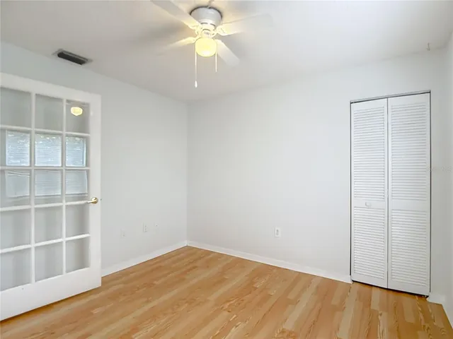 an empty room with wooden floor closet and windows
